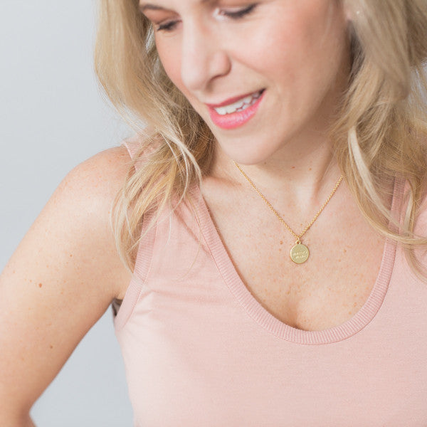 Blonde woman wearing pink shirt and inspirational necklace