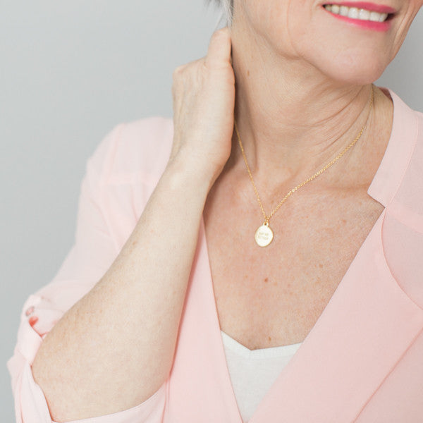 close up photo of blonde woman wearing inspirational necklace and pink shirt