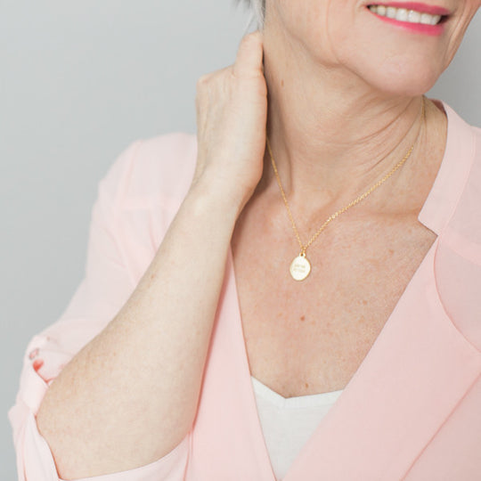 close up photo of blonde woman wearing inspirational necklace and pink shirt