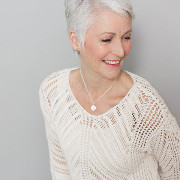 white haired woman wearing necklace supporting charity